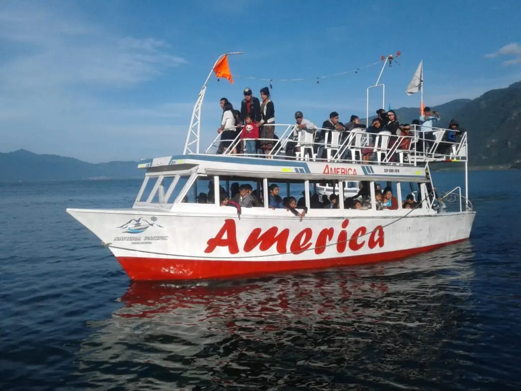 Lancha turística navegando en el lago de Atitlán con pasajeros a bordo