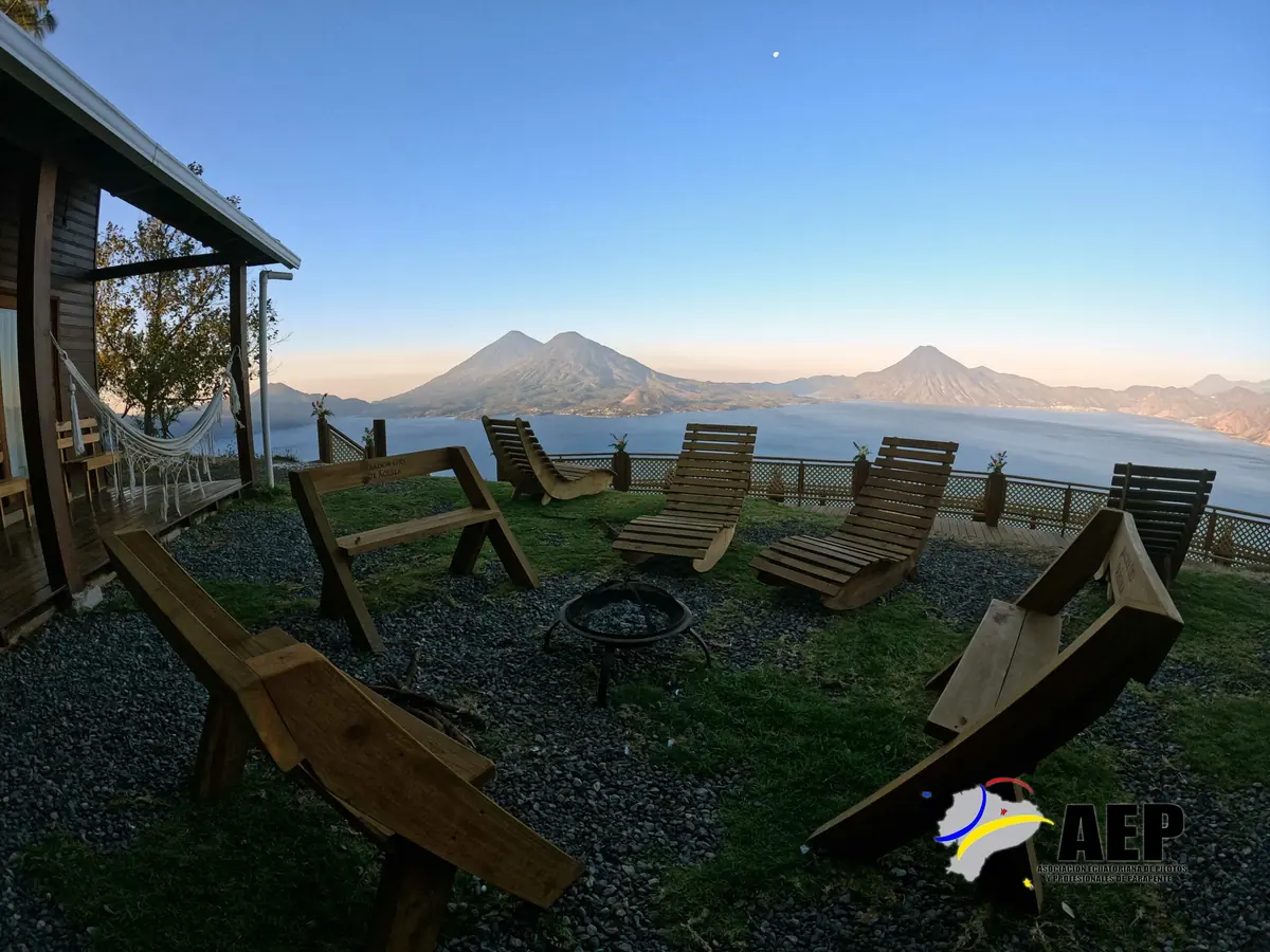 Terraza del mirador al atardecer, con sillas de madera frente a los volcanes y el lago